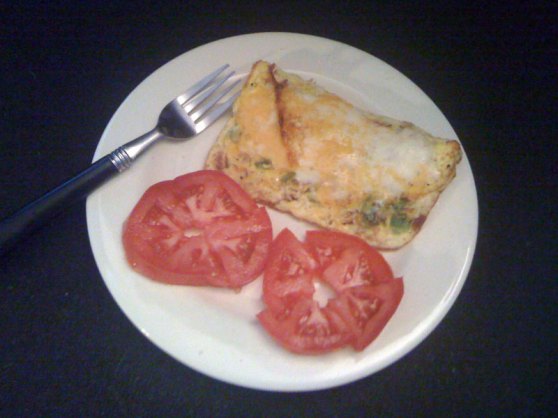Square-shaped omellette for one with tomato slices and a fork resting on the side of the plate